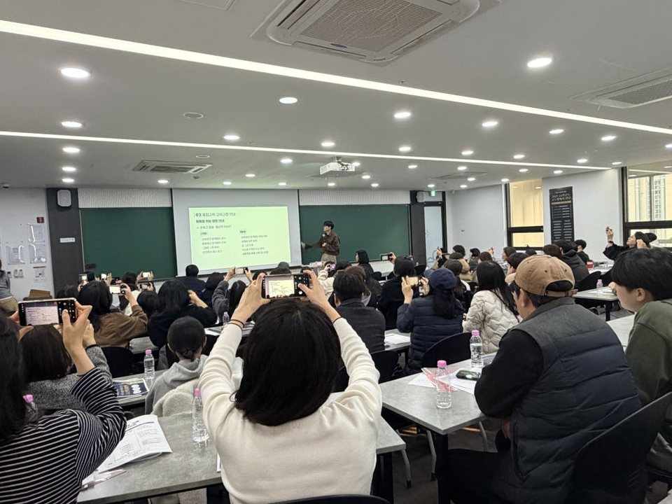 설명회에서 학부모님들이 발표 화면을 휴대폰으로 찍는 모습