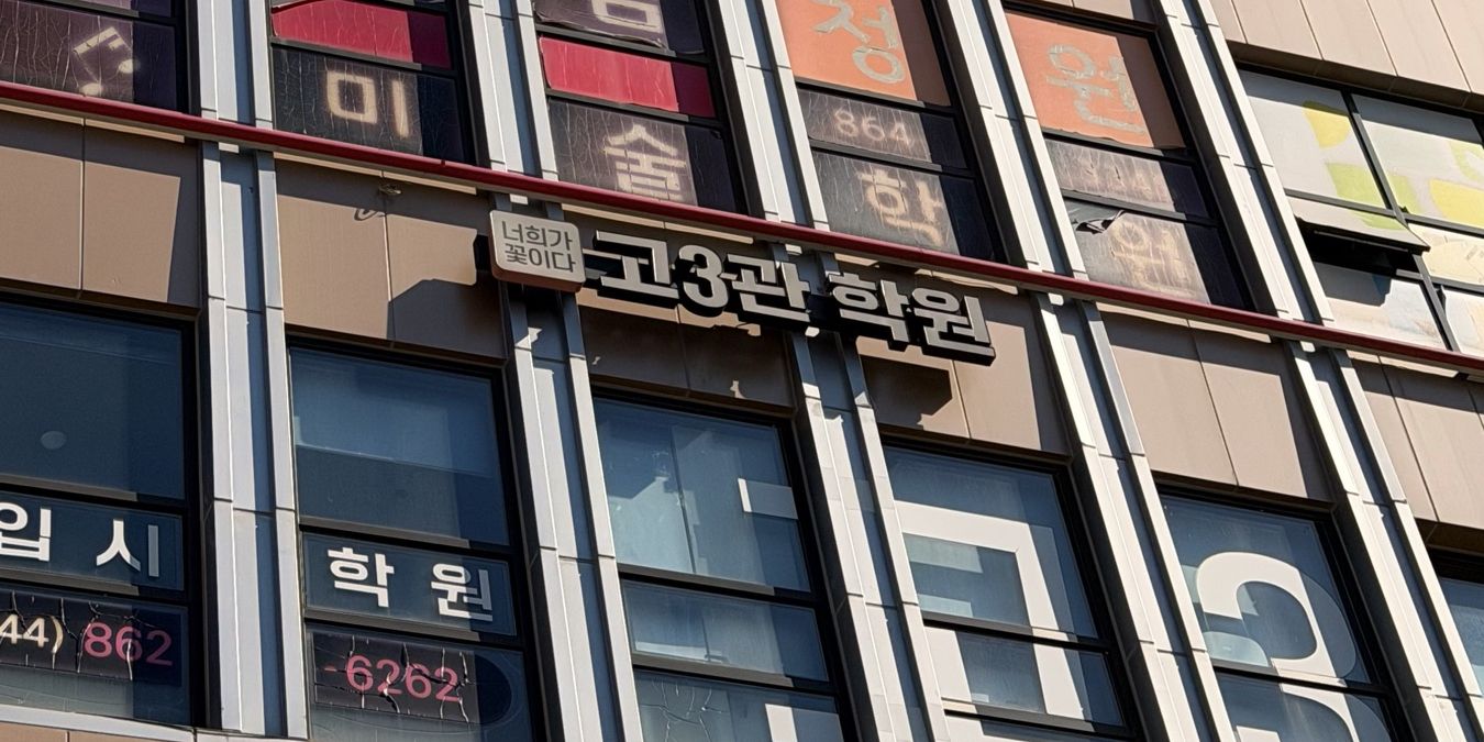 다정프라자 건물 4층 바깥의 「너희가 꽃이다 고3관 학원」 간판과 창에 붙은 학원 전화번호